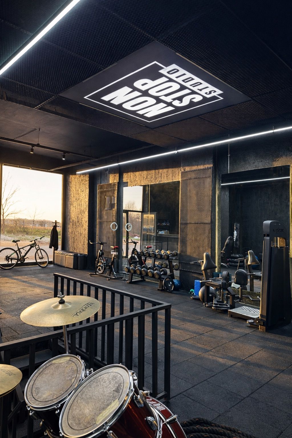 Non Stop GYM salon içi: siyah dokulu duvarlar, ışıklı tabela ve ekipmanlar